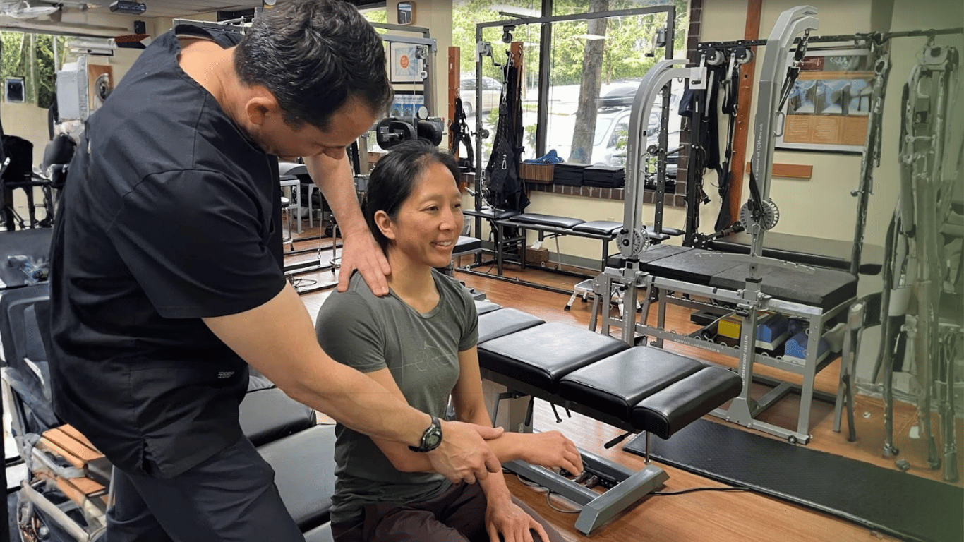 bellevue chiropractor | Dr cummins with patient stretching her arm standing in front of chiropractic equipment