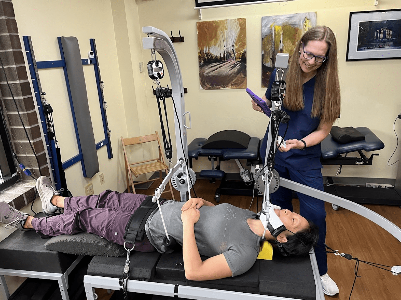 female doctor in scrubs standing above a patient on a chiropractic table