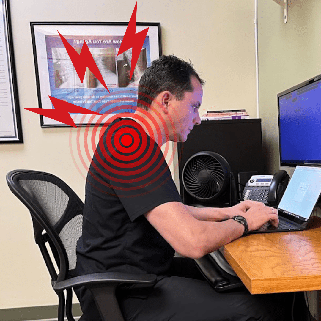 A man sits at a desk working on a laptop with red pain symbols and concentric circles highlighting discomfort in his upper back, shoulder, and neck pain areas.