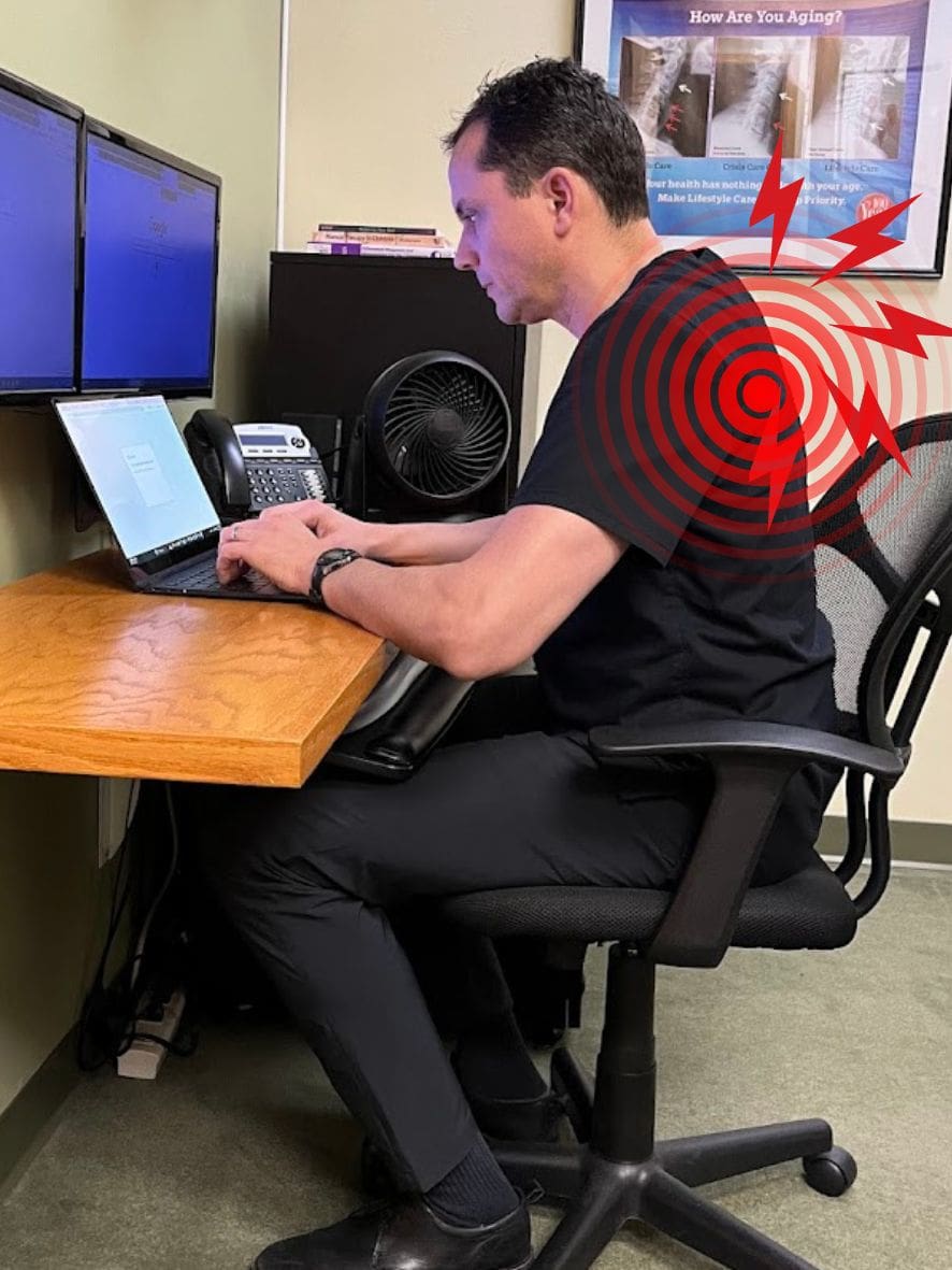A man sits at a desk working on a laptop, with red pain target graphics highlighting discomfort in his upper back, suggesting the need for Mid Back Pain Treatment due to poor posture.