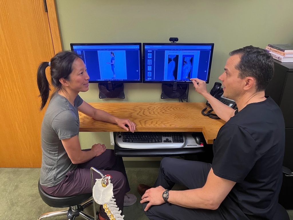 chiropractic care for chronic pain | malew doctor examining xrays with female patient in front of computer screen