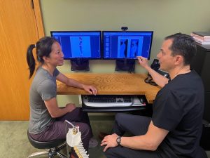 chiropractic care for chronic pain | malew doctor examining xrays with female patient in front of computer screen