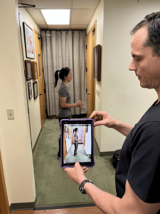 doctor using an ipad to take images of patient assessing posture with chiropractic tool